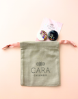 Colorful round scarf magnet brooches with in navy and white with sparkle accents on a light pink background
