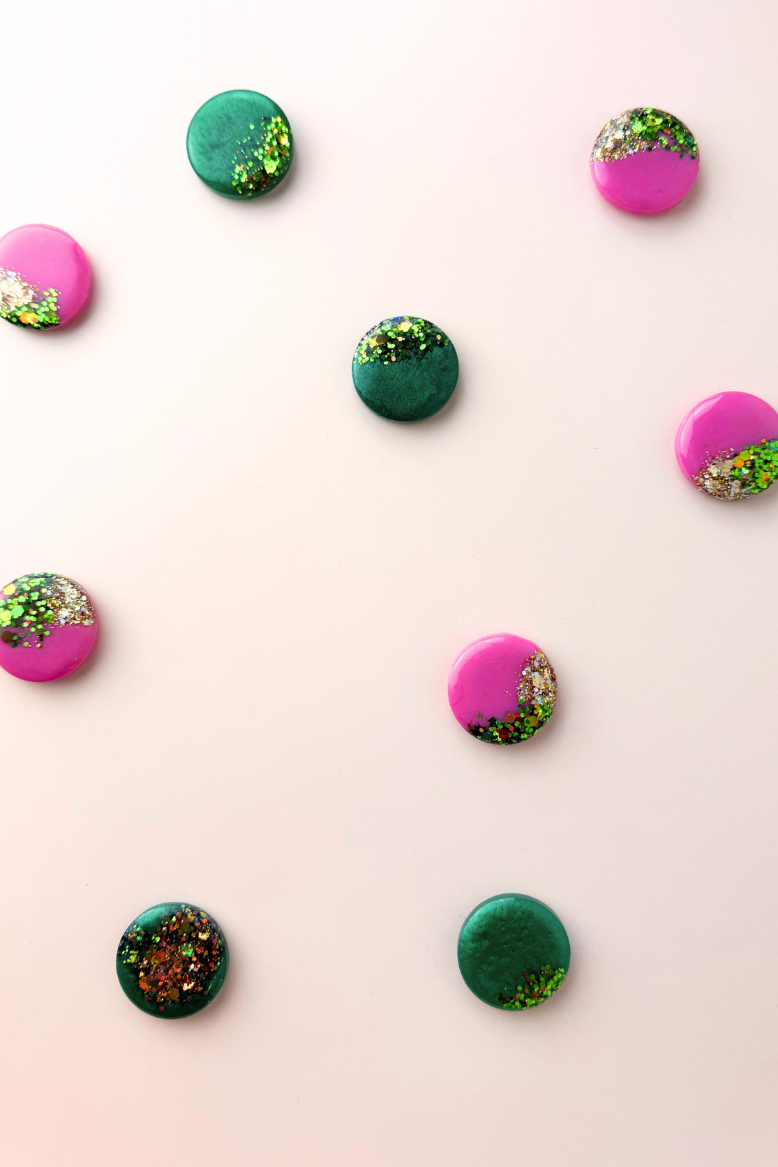 Colorful round scarf magnet brooches with green and pink accents on a light pink background